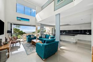 a living room with blue couches and a kitchen at Villa Mariposa in Coolum Beach
