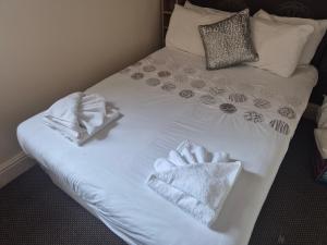 a bed with white sheets and towels on it at White Moon Hotel in Blackpool +6 photos