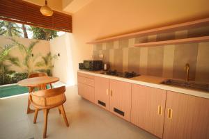 a kitchen with wooden cabinets and a table and chair at enn Collection in Kuta Lombok