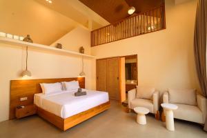 a bedroom with a bed and a couch and a chair at enn Collection in Kuta Lombok +38 photos