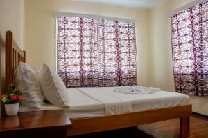a bedroom with a bed and two large windows at Tanuli Heights in Honiara