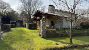 a house with a stone chimney on a yard at Cabañas Hueney Ruca in Sierra de la Ventana