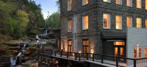 a building next to a river with a waterfall at Wally’s Matchbox |New|Hot Tub|Fire Pit|Close 2 All in Hawley