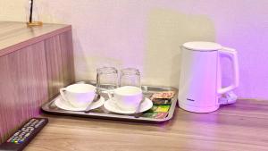 a tray with cups and saucers and a coffee maker at Premium Yunusobod Hotel in Darkhon