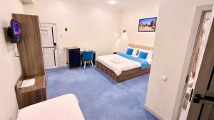 a bedroom with a bed and a desk with a television at Premium Yunusobod Hotel in Darkhon