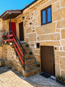 a stone house with a red door and stairs at Casa Aninhas in Sabrosa +10 photos