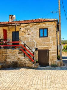 a stone house with a red door and a red railing at Casa Aninhas in Sabrosa
