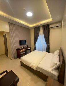 a bedroom with a bed and a desk and a television at Degrams Hotel and suites in Epe