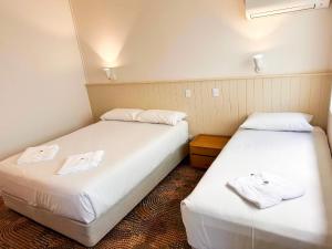 two beds in a room with white sheets and towels at Bateau Bay Hotel in Bateau Bay