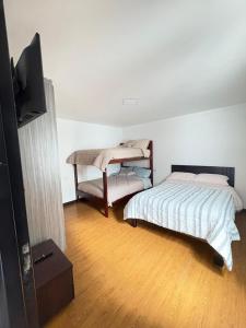 a bedroom with a bed and a flat screen tv at La Posada del Colibrí in Cuenca