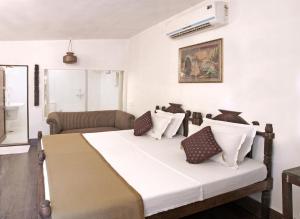 a bedroom with a bed with white sheets and pillows at Mandore Guest House in Jodhpur