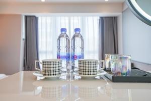 two bottles of water sitting on a table with two cups at Modern Space Hotel--Guangzhou Nansha Wanda Plaza in Guangzhou