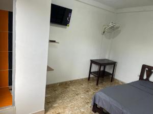 a room with a bed and a table and a tv at Hotel Don Franco in Villagarzón