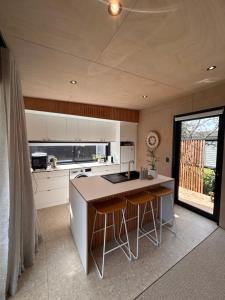 a kitchen with a counter and stools in it at Cooks Beach Studio Escape in Cooks Beach