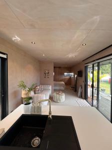 a kitchen with a sink and a living room at Cooks Beach Studio Escape in Cooks Beach +1 photo