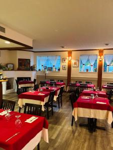 a dining room with red tables and chairs and windows at Auberge du Grand Lac in Magog-Orford