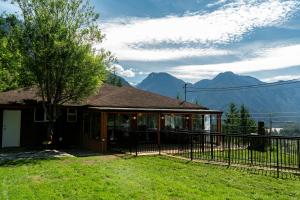 a house with a fence and mountains in the background at Mountain Retreat Hope in Hope
