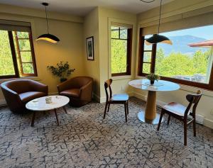 a living room with chairs and tables and windows at Artisan Suites on Bowen in Bowen Island