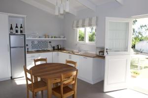 a white kitchen with a wooden table and chairs at Paul Wallace Wines & Cottages in Elgin