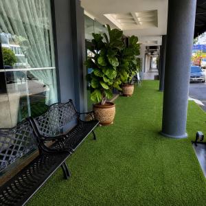 a black bench sitting on a balcony with green grass at Royal Queenspark Hotel in Malacca