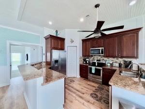 a kitchen with wooden cabinets and stainless steel appliances at Sandy Beach Retreat and Gulf View in Galveston +31 photos