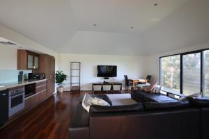 a living room with a black couch and a kitchen at The Siding Yallingup in Yallingup