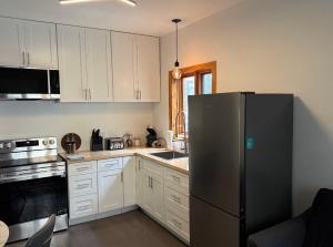 a kitchen with white cabinets and a stainless steel refrigerator at La Pergola-6 in Quebec City