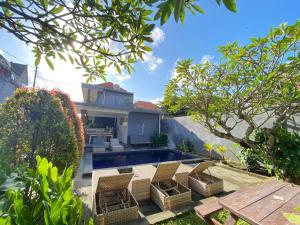 a backyard with a pool and chairs and a house at The Lonceng hotel in Badung