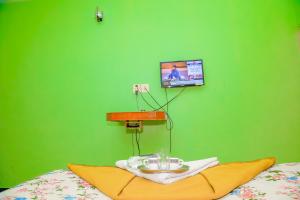 a green wall with a table on a bed at Park Palace Inn in Erode +39 photos