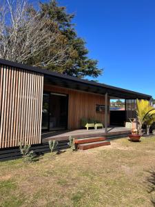 a house with a large deck with two green chairs at Cooks Beach Studio Escape in Cooks Beach