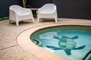 a turtle swimming in a pool with two chairs at Caboolture Gateway Motel in Caboolture