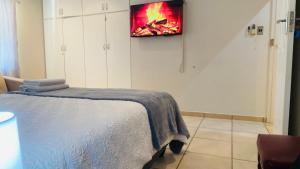a bedroom with a bed and a tv on the wall at The Oasis Guesthouse in Mtubatuba
