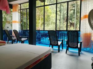 a room with chairs and a bed and windows at komalie resort in Kitulgala +5 photos