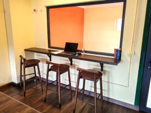 a room with a desk with a laptop and stools at Rebel Rooster Hostel in Hanoi
