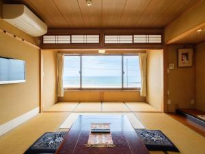 a room with a large window with a view of the ocean at Minshuku Meiwaso in Takaoka