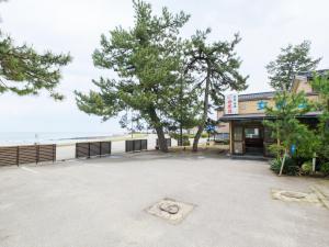 a parking lot in front of a building with a tree at Minshuku Meiwaso in Takaoka