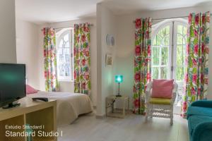 a bedroom with a bed and a tv and two windows at Akisol Vilamoura Gold in Vilamoura