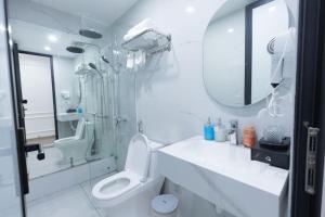 a white bathroom with a shower and a toilet at Anna Noi Bai Airport Hotel in Sóc Sơn +36 photos