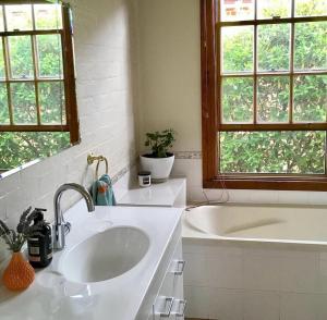 a bathroom with a sink and a bath tub at Charming Heritage Cottage in Armidale