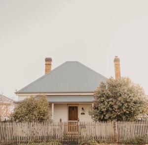 a white house with a white picket fence at Charming Heritage Cottage in Armidale