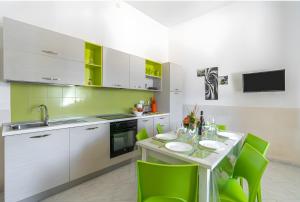 a kitchen with green accents and a table with green chairs at Villa Anny con idromassaggio in Avola +36 photos