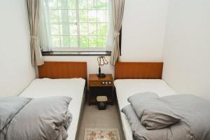two twin beds in a room with a window at ラリックス蓼科 in Chino