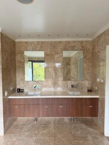a bathroom with two sinks and two mirrors at The Siding Yallingup in Yallingup