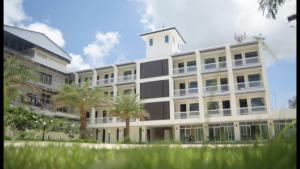 a large white building with palm trees in front of it at Panatara Chumphon in Chumphon