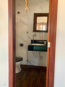 a bathroom with a toilet and a sink and a mirror at Casa Verde Canoa Quebrada in Canoa Quebrada