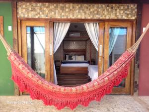 a hammock in a bedroom with a bed at Casa Verde Canoa Quebrada in Canoa Quebrada
