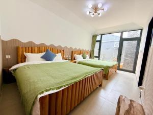 a bedroom with two beds with green sheets and a window at Gubeikou Great Wall Yunyeshu Boutique Guesthome in Miyun