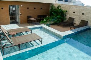 a swimming pool with two chairs and a table at Loft Icarai in Niterói