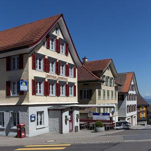 un grand bâtiment avec volets rouges dans une rue dans l'établissement Pizzeria-Pension Gambrinus, à Walzenhausen