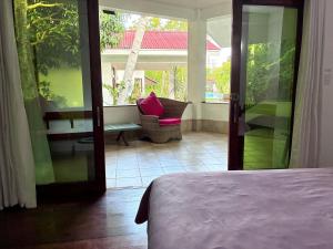 a room with a bed and a patio with a chair at Villa Formosa Panglao in Panglao Island